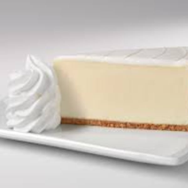 A slice of classic cheesecake with a graham cracker crust and a dollop of whipped cream.