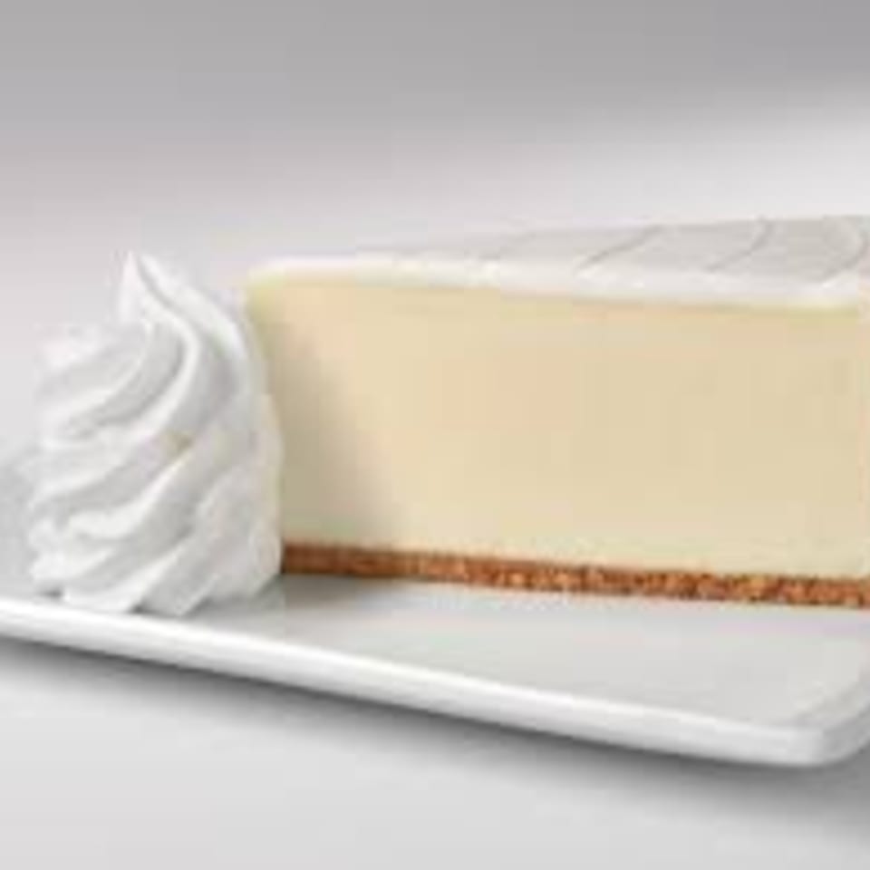 A slice of classic cheesecake with a graham cracker crust and a dollop of whipped cream.