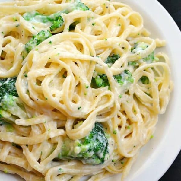 Creamy Italian pasta with broccoli florets on a white plate from Green Olive Restaurant.