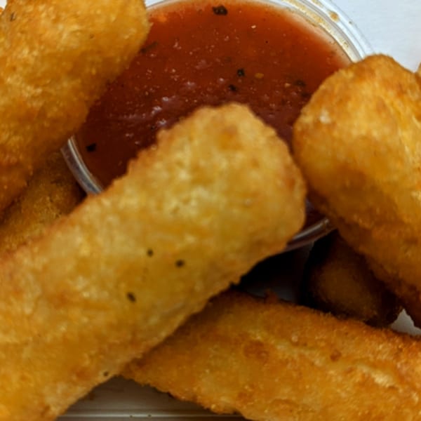 Golden-brown mozzarella sticks arranged around a small container of red marinara dipping sauce.